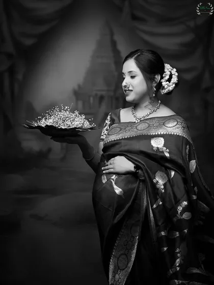 A traditional and regal portrait of a mother-to-be in a beautiful saree, presented in timeless black and white.