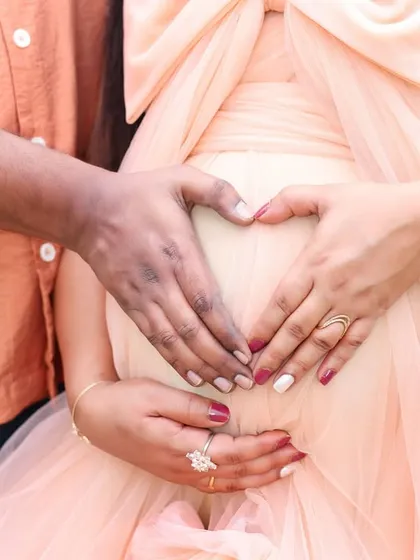 A close-up of a couple's hands forming a heart on the baby bump, a simple yet powerful symbol of their love.
