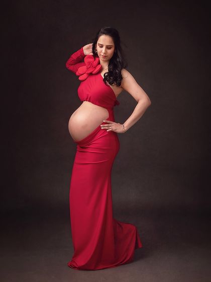 A powerful and artistic pose in a red cutout gown. This portrait celebrates the mother's body with confidence and style.