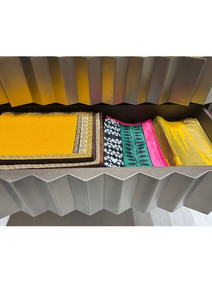 A drawer neatly organized with a collection of colorful placemats and table runners.