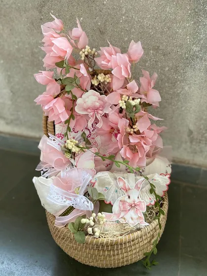 A delicate and pretty-in-pink baby girl hamper. This basket is overflowing with soft pink florals and lace-trimmed baby items, making it a timeless and elegant gift.