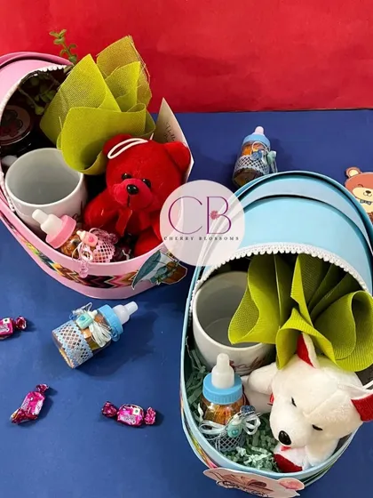 Our baby shower hampers in cradle baskets are perfect for celebrating a new arrival. We offer them in both pink and blue, filled with items like a teddy bear, a mug, and chocolate-filled baby bottles.