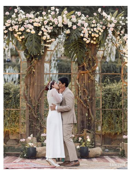 The first kiss as a married couple, framed by a stunning floral arch. This is a peak emotional moment, captured with a sense of joy and finality. The perfect end to a beautiful ceremony.
