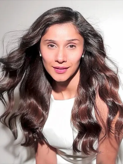 A portrait of the client with her new rich, reddish-brown hair. The wind-blown effect shows the hair's movement and soft texture.