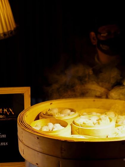 Freshly steamed dim sums ready to be served. This moody shot captures the steam rising from the bamboo baskets, highlighting the freshness and authenticity of our Pan-Asian offerings.