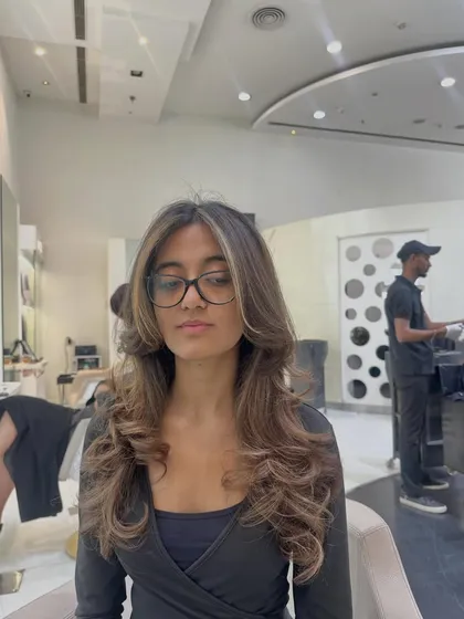 A front-facing view of the same subtle brunette refresh. You can see how the gentle highlights brighten her features, and the soft curls at the ends add volume and movement.
