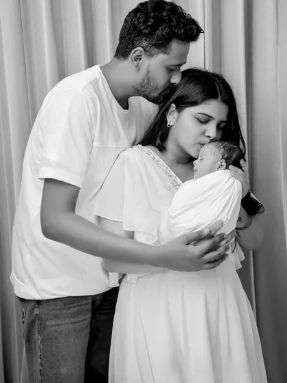 A tender black and white moment where both parents are kissing their newborn's head. This image beautifully captures the overwhelming love and affection in a new family.