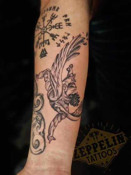 A "Fallen Angel" tattoo, designed to fit between other existing pieces on the client's forearm. The dynamic pose and detailed wings were key to this design.