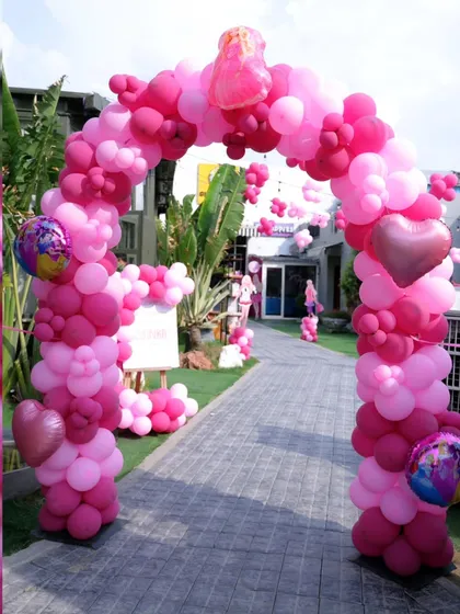 A grand balloon arch in shades of pink welcomes guests to a fabulous Barbie-themed birthday party. We use foil and heart-shaped balloons to add extra sparkle.