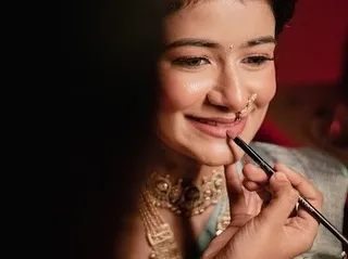 A candid, behind-the-scenes moment during an engagement makeup session. This artistic shot captures the final touch of lipstick application, highlighting the detail and care I put into creating a perfect, soft glam look for my client.