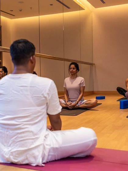 An instructor guides a Hatha yoga class in our indoor studio. The mirrored wall helps participants refine their alignment, while the calm, focused environment is perfect for deepening your practice regardless of the weather.