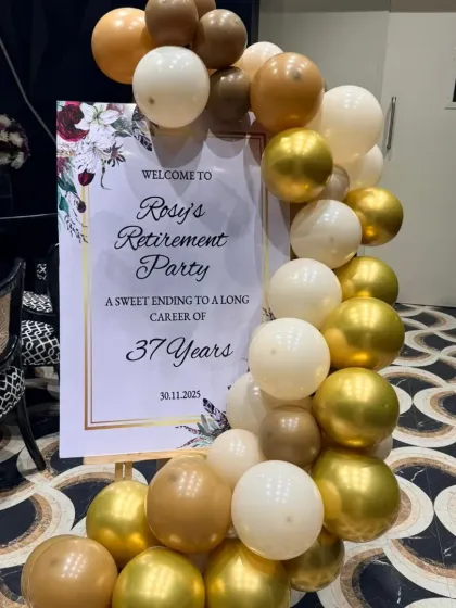 A personalized welcome sign is essential for making guests feel special. This elegant sign for Rosy's retirement party, framed by a gold and white balloon garland, beautifully honoured her 37-year career.