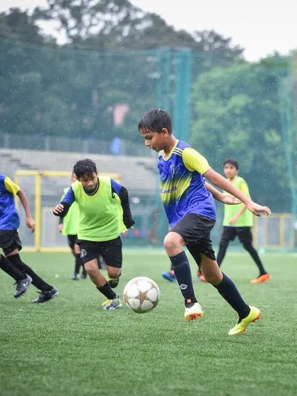 Players are fully engaged in a training match during a rainy day. This demonstrates our philosophy of building resilience and skill in all weather conditions.