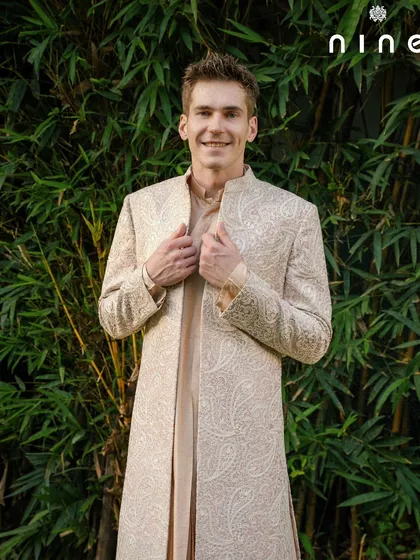 A happy client showcasing the full length of the open sherwani. The way it drapes over the kurta creates a layered, sophisticated look that is both traditional and refreshingly modern.