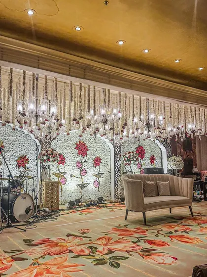 The stage for the live band at the ITC Maurya Sangeet was set against a backdrop of white floral walls and hanging crystals, blending performance energy with soft, romantic decor.