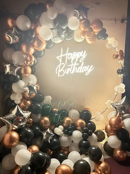 Even a simple corner can be transformed into a stylish photo booth. For this birthday, I created a full balloon arch in black, white, and rose gold, with a central neon sign to make it pop.