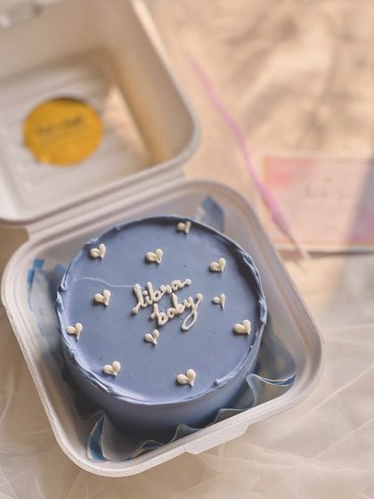 Celebrate a star sign with a custom bento. This periwinkle blue cake for a "libra baby" is decorated with small white hearts for a dreamy, astrological theme.