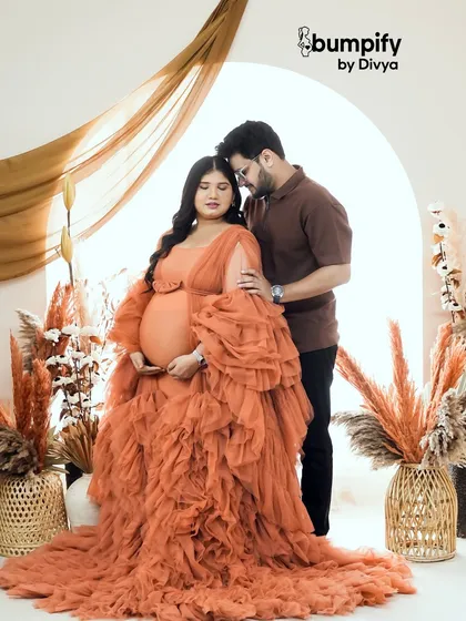 A warm and romantic portrait of a couple in our earthy, boho-inspired studio set. Her flowing orange ruffled gown adds a beautiful pop of color to the neutral tones.