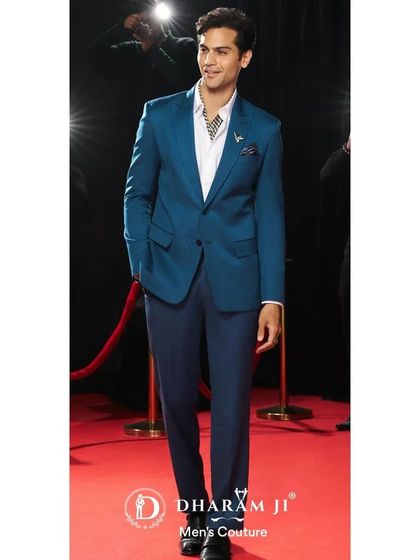 A model on the red carpet in a striking teal blue suit. The color is bold yet sophisticated, making it an excellent choice for making an impression at any event.