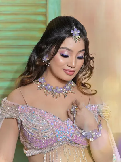 An eyes-closed portrait highlighting the purple-toned eye makeup that perfectly matches the floral jewellery.