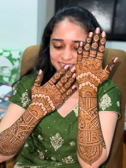 This beautiful bride is all smiles as she shows her intricate mehendi. The design is a lovely mix of traditional patterns, perfect for her wedding celebrations.