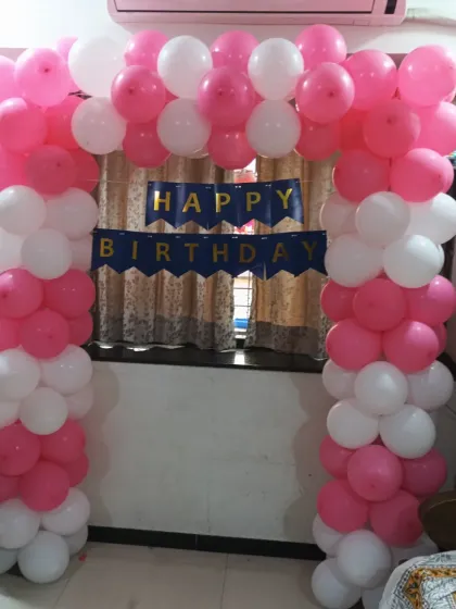 A pink and white balloon gate arch, perfect for welcoming guests or framing a cake-cutting area in a home party setting in Seawoods, Navi Mumbai.