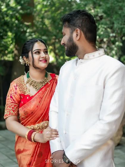 A couple shares a look of love. Her vibrant red saree and his clean white sherwani create a classic and striking combination for any celebration.