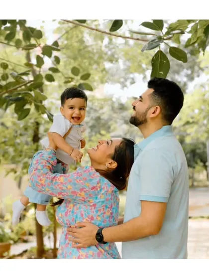 Using the natural frame of tree leaves, this shot captures a mother lifting her baby up to his father. The genuine smiles and beautiful greenery make for a perfect candid family moment.