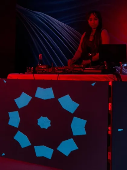 Mixing tracks at a private event with a custom-designed DJ booth. The lighting shifted from red to blue, creating a dynamic visual experience for the guests.