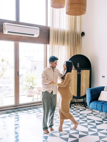 A wider angle of the couple dancing in their living room. This shot captures the full environment, showing their beautiful home and their joyful interaction within it.
