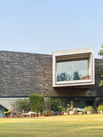 The Rhizome House, a farmhouse project completed in 2016. Here, a cantilevered volume clad in wooden shingles projects out from the main structure, framing a view of the landscape and demonstrating a blend of heavy concrete and lighter materials.