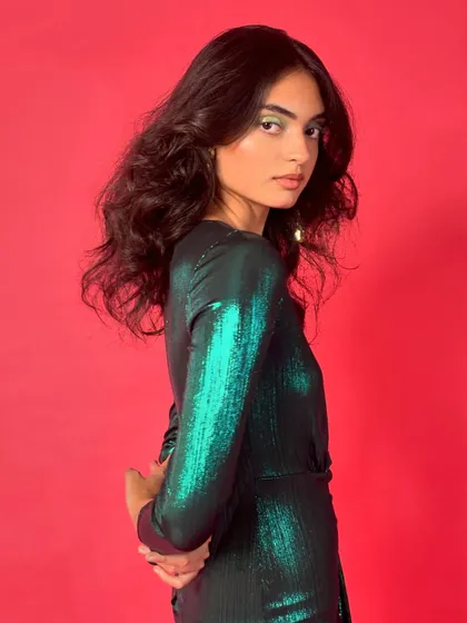 A closer look at the metallic green dress, highlighting its shimmering texture and flattering silhouette. The simple styling lets the dress speak for itself.