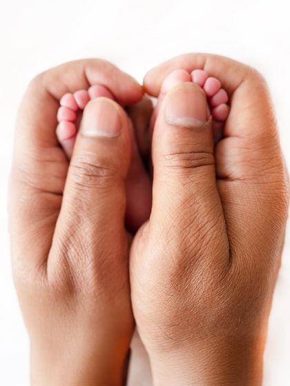 A parent's hands gently holding their newborn's tiny feet. This pose beautifully illustrates the scale of how small and precious a new baby is.