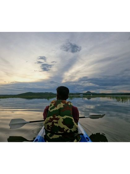 A stunning view from the kayak, with sun rays peeking through the clouds over the distant hills.