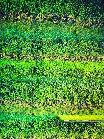 This green wall features horizontal stripes of different textures and shades of green. It's a simple way to add visual interest to a large, flat surface in an office or home.