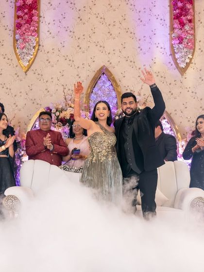 A celebratory wave from the newly engaged couple, standing in a cloud of smoke after their ring ceremony.