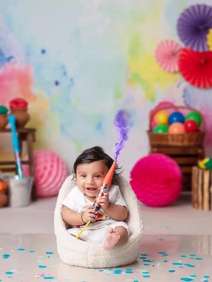 A baby boy plays with a pichkari, a big smile on his face, in our colorful and safe Holi setup.