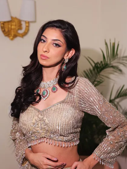 A direct, confident look from a model in our sparkling gold lehenga. The intricate beadwork on the blouse and the statement jewelry create a powerful look.