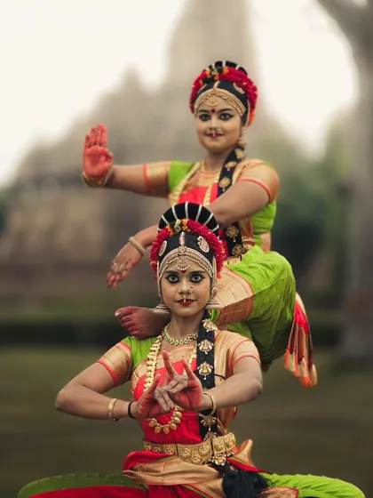 A dynamic pose by two Kuchipudi dancers, capturing their energy and grace against the historic backdrop of Khajuraho.