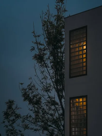 This series of images shows how the home's exterior transforms from day to night. The glass block walls, which provide privacy during the day, become luminous features in the evening, creating a warm and inviting aura.