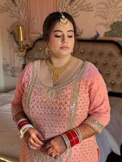 A full view of her pastel pink sharara suit. The makeup is kept soft and monotone to complement the intricate outfit and heavy jewelry.
