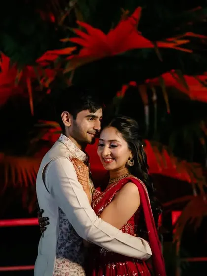 A vibrant portrait from a sangeet night. The red backlighting adds energy and drama, perfectly matching the celebratory mood of the event.