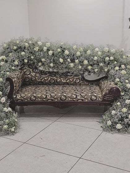 For an intimate engagement ceremony at home, I decorated this sofa with a beautiful arch of baby's breath and white roses, turning a simple space into a special photo spot.