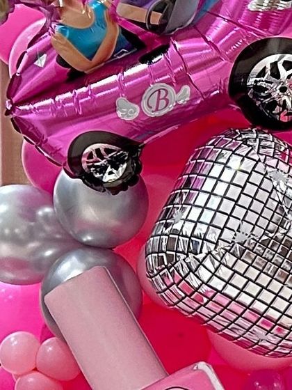 Fun and sparkly details from a Barbie party, including a pink car foil balloon and a silver disco ball balloon.