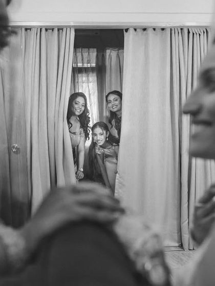 Friends and family peeking through the curtains to get a glimpse of the bride. A fun, candid moment that captures the excitement of the day.