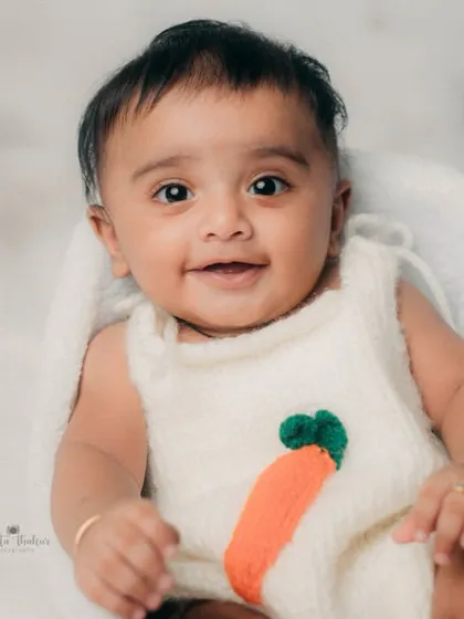 This 5-month-old's smile can light up any room. The simple, cloudy white background and carrot-themed outfit make his expression the star of the show.