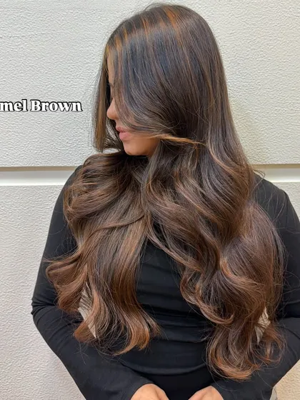 A side profile of the finished caramel brown look, showing how the layers and color work together. The face framing pieces are lighter to brighten her complexion, creating a soft and flattering style.