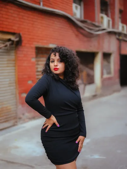 A duplicate of image 311, this portrait of a model in a black dress against a gritty urban background emphasizes her confident stance.