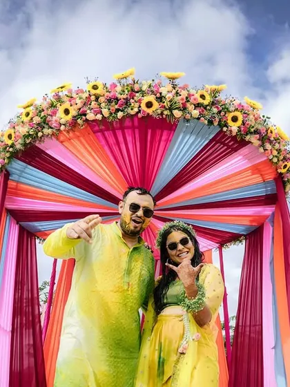 The couple looking cool and happy under their colorful Haldi canopy, ready for the festivities.