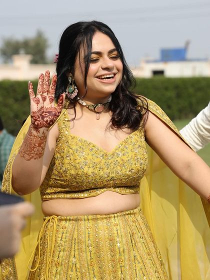 A happy bride at her afternoon mehendi function. Tusharika is styled in an off-beat chartreuse lehenga from Odhni World, paired with fun, eclectic jewelry from Mahira Jewels.